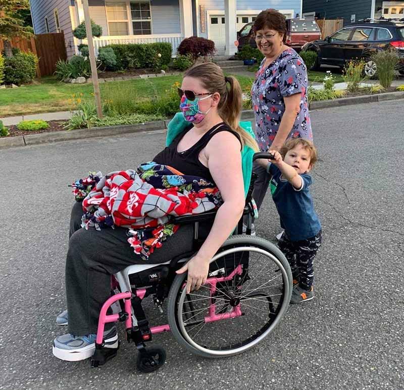 多米尼克推着克里斯蒂·诺维洛坐在轮椅上，他们的家庭保姆陪着他们晚上散步. (图片由Jorge Novillo提供)